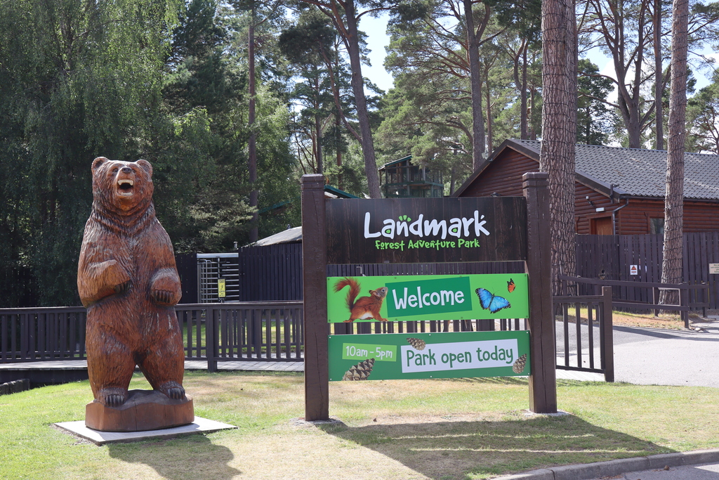 Bear sculpture and welcome sign at Landmark Forest Adventure Park Carrbridge
